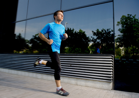 young attractive man running and training on urban street background on summer workout in sport practice and healthy lifestyle conceptの写真素材