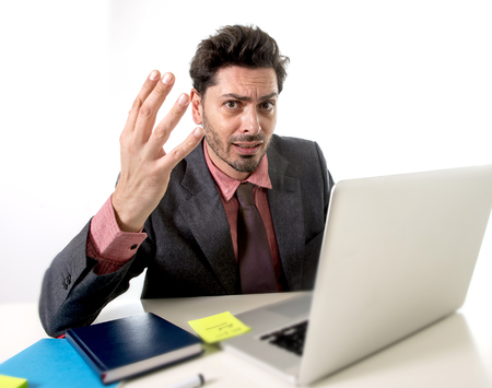 young attractive businessman sitting at office desk working on computer laptop covering his face...