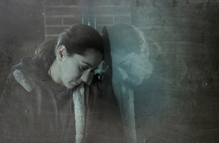 sad woman alone leaning on street window at night looking desperate suffering depression crying in pain lonely and lost as violence and abuse female victim or addict concept grunge dirty editの写真素材