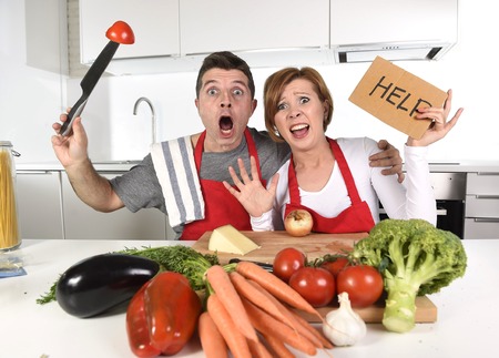 young attractive American couple in stress at home kitchen looking lost and frustrated wearing apron asking for help unable to cook in amateur newbie inexperienced and rookie home cooking messの写真素材