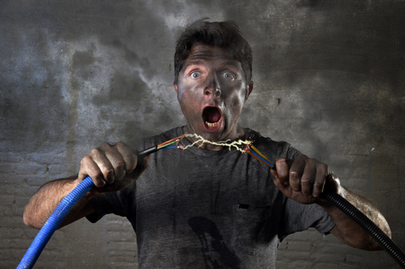 young untrained man joining electrical cable suffering domestic accident with dirty burnt face in...