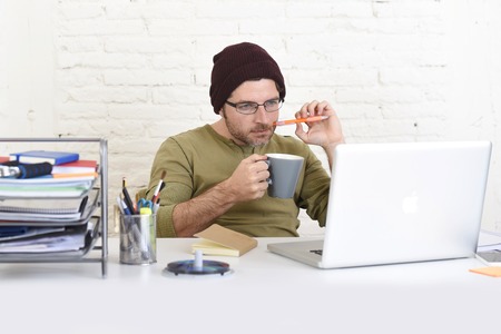 young hipster businessman working from his home office as freelancer wearing casual beanie and glasses looking busy in self employed business model successの写真素材
