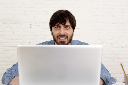corporate portrait of young hispanic attractive hipster businessman on his 30s working at modern home office with computer laptop in creative freelancer and self employed business modelの写真素材