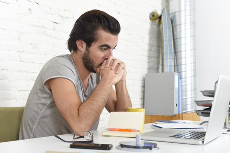 young student preparing exam thinking or informal hipster style businessman working with laptop computer at home office looking thoughtful in new business and lifestyle conceptの写真素材