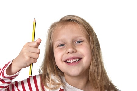 sweet beautiful female child 6 to 8 years old with cute blonde hair and blue eyes holding pencil isolated on white background in education and primary or junior school supplies conceptの写真素材