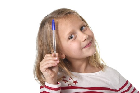sweet beautiful female child 6 to 8 years old with cute blonde hair and blue eyes holding ball pen isolated on white background in education and primary or junior school supplies conceptの写真素材