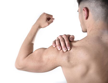 young muscular sport man holding sore shoulder with hand touching or massaging in workout stress body pain and health problem isolated on white backgroundの写真素材