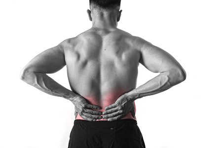 young muscular body sport man holding sore low back waist with hands  suffering pain in athlete...