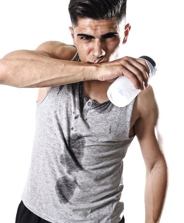 close up portrait of young athletic sport man thirsty holding bottle of water  with sweaty face and wet singlet after refreshing and recovering after hard training workout in hydration conceptの写真素材