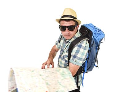young tourist man reading city map looking lost and confused loosing orientation carrying backpack wearing summer hat and sunglasses disoriented  face expression isolated white backgroundの写真素材