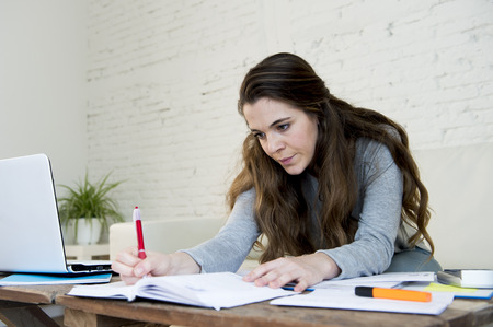 young attractive and desperate woman suffering stress doing domestic accounting paperwork bills and...