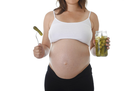 young pregnant woman showing big belly holding olives jar and fork with pickle isolated on white background in pregnancy whim food concept isolated on white backgroundの写真素材