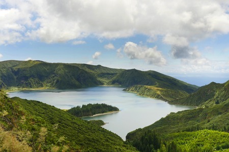 amazing landscape view of crater volcano lake in Sao Miguel island of Azores in Portugal with green mountains and beautiful turquoise color water reflecting sky in holiday destinations and travel conceptの写真素材