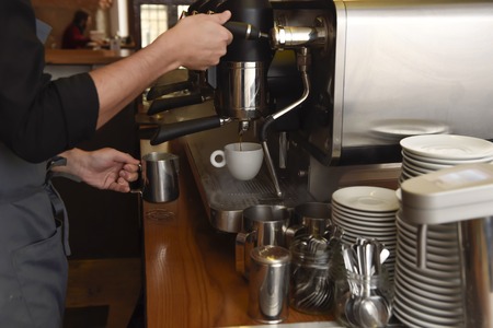 expert barista close up hands preparing delicious coffee cream operating machine at coffee shop restaurant in cafe preparation conceptの写真素材