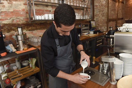 young italian barista or coffee maker at restaurant shop preparing delicious milk cream at cafe machine in professional staff worker conceptの写真素材