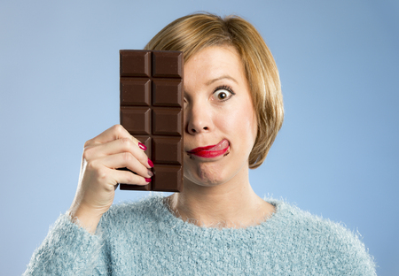 young cute happy woman holding big chocolate bar with mouth stains and crazy excited face expression...