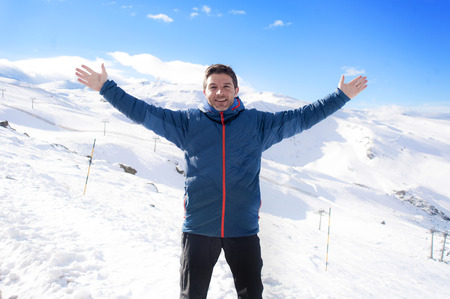 young happy man doing victory sign after peak summit trekking achievement in snow mountain on winter...