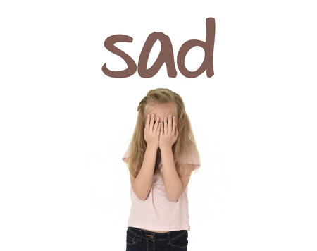English language learning vocabulary school card with word sad and sweet young little schoolgirl covering her face with her hands crying sad victim of bullying at school isolated on whiteの写真素材