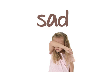 English language learning vocabulary school card with word sad and sweet young little schoolgirl covering her face with her hands crying sad victim of bullying at school isolated on whiteの写真素材