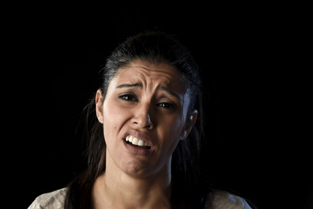 young attractive sad and desperate Latin woman crying frustrated suffering pain and problems grieving in stress and sorrow in facial expression of sadness emotion isolated on black backgroundの写真素材