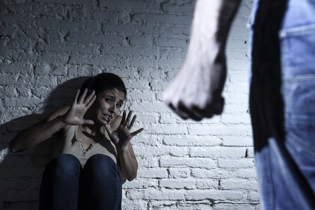 young couple in problems with drunk husband or man attacking and threatening wife or girl crying on the floor scared and terrified in domestic violence and cruel abuse of womenの写真素材