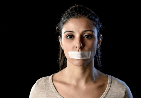 close up portrait of young attractive woman with mouth and lips sealed in adhesive tape restrained and abused censored and banned to speak and express opinion in freedom conceptの写真素材