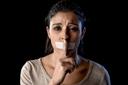 close up portrait of young attractive woman with mouth and lips sealed in adhesive tape restrained and abused censored and banned to speak and express opinion in freedom conceptの写真素材