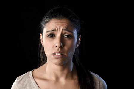 young attractive sad and desperate Latin woman crying frustrated suffering pain and problems grieving in stress and sorrow in facial expression of sadness emotion isolated on black backgroundの写真素材