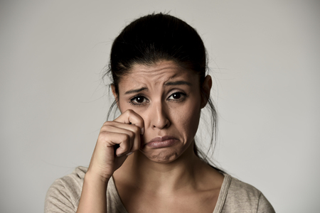 young beautiful hispanic sad woman serious and concerned crying feeling depressed isolated grey background in sadness and sorrow emotionの写真素材