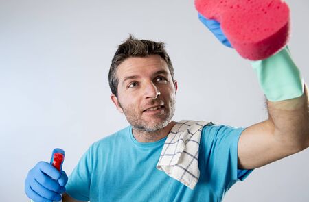 portrait of domestic service man or busy husband smiling happy doing house cleaning with spray...