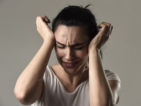 beautiful face of sad woman crying desperate and depressed with tears on her eyes suffering pain and depression isolated on grey background in sadness facial expression and emotion conceptの写真素材