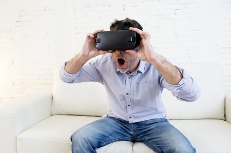 young modern man at home living room sofa couch excited using 3d goggles watching 360 virtual reality vision enjoying the fun cyber experience in vr simulation reality conceptの写真素材
