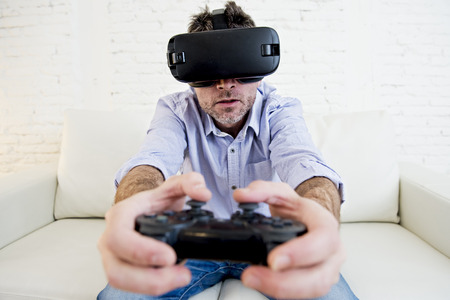 young modern man at home living room sofa couch playing video game excited using 3d goggles watching...