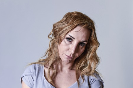 blond attractive woman on her thirties sad and depressed looking at the camera in sorrow and grief facial expression in female depression emotion concept isolated on grey backgroundの写真素材