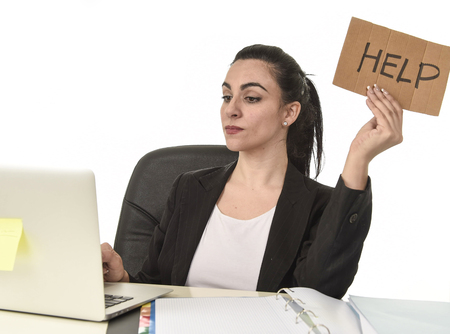 young attractive latin woman showing help sign desperate suffering stress at work while sitting at office laptop computer desk in business overwork female feeling stressed and overwhelmedの写真素材
