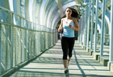 young beautiful and athletic sport woman running and jogging in urban training workout crossing modern metal city bridge in female runner body care and healthy lifestyle conceptの写真素材