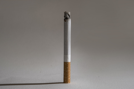 one cigarette and shadow isolated on white background in unhealthy dangerous habit of tobacco and...