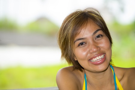close up portrait of young happy and beautiful expressive Asian woman smiling excited and nice in positive face expression and happiness concept outdoors in nature backgroundの写真素材