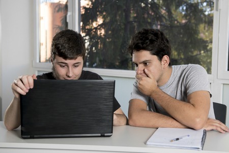 two male teenager university students working on school classroom with laptop computer together on project in education and academic success conceptの写真素材