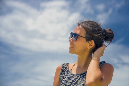 young happy and excited Asian Chinese woman posing alone isolated on a Summer blue sky looking cheerful and relaxed enjoying and having fun in positive attitudeの写真素材