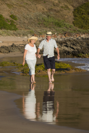 lovely senior mature couple on their 60s or 70s retired walking happy and relaxed on beach sea shore in romantic aging together and retirement husband and wife lifestyle conceptの写真素材