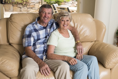 senior beautiful middle age couple around 70 years old smiling happy together at home living room sofa couch looking sweet in lifetime husband and wife enjoying life and love concept の写真素材