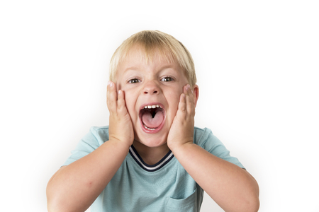portrait of 3 years old little blond kid with mouth open screaming surprised or scared holding his head with his small hands isolated on white background in facial expression and emotions conceptの写真素材