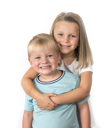 7 years old adorable blond happy girl posing with her little 3 years old brother smiling cheerful isolated on white background in children and siblings relationship conceptの写真素材