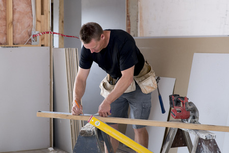 happy attractive and confident constructor carpenter or builder man working and measuring at...