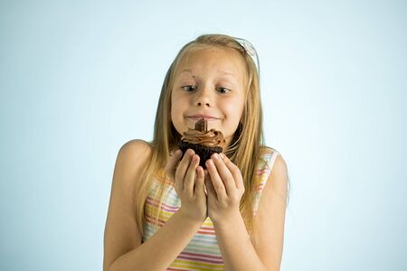 young beautiful happy and excited blond girl 8 or 9 years old holding chocolate cake on her hand looking spastic and cheerful in sugar calories and unhealthy sweet nutrition abuse addiction conceptの写真素材