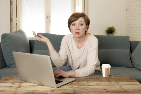 young attractive and busy woman at home sofa couch doing some laptop computer work in stress looking worried in entrepreneur lifestyleの写真素材