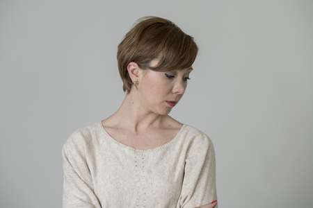 young pretty and sad red hair woman looking worried and depressed crying and suffering pain and depression in life problem concept isolated on even background studio portraitの写真素材