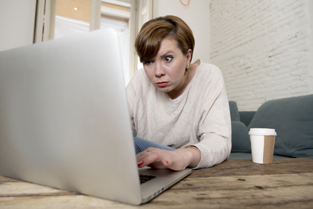 young attractive and busy woman at home sofa couch doing some laptop computer work in stress looking worried in entrepreneur lifestyleの写真素材