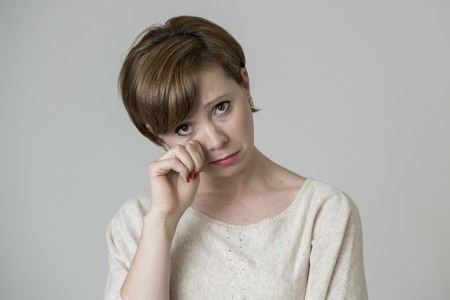 young pretty and sad red hair woman looking worried and depressed crying and suffering pain and depression in life problem concept isolated on even background studio portraitの写真素材